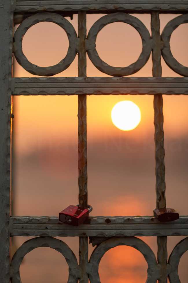 Lock hanging over bridge at sunrise